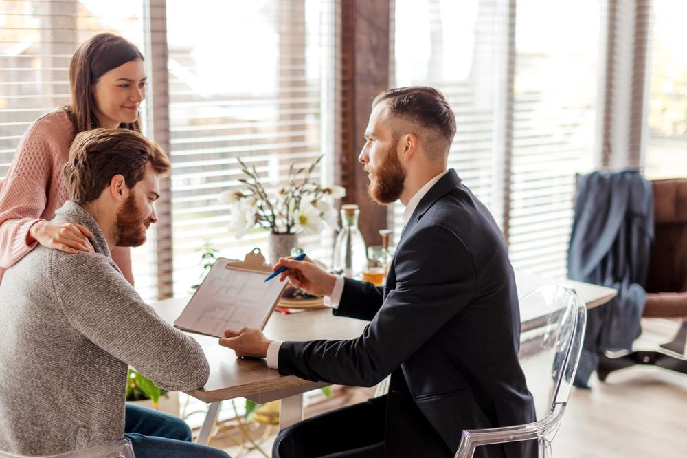 trois personnes autour d'une table montrant un document